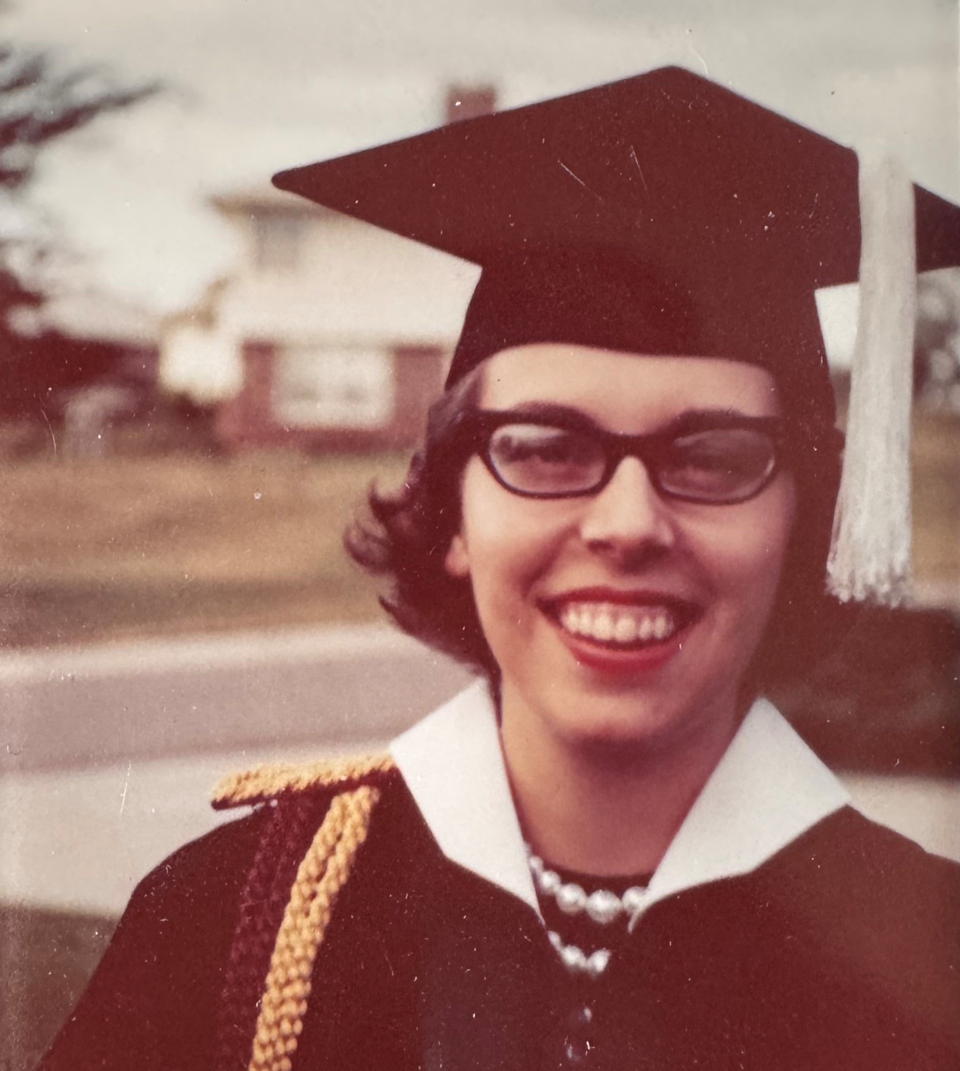 Marcia at her graduation, smiling in cap and gown
